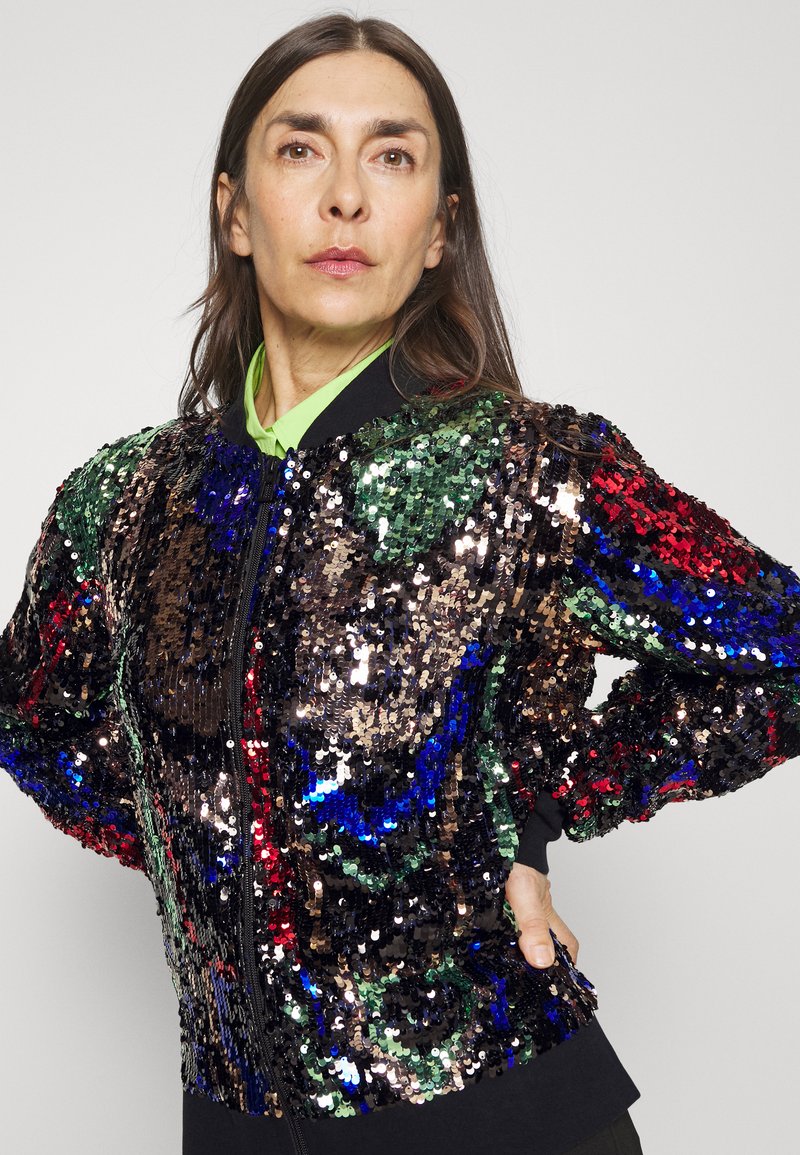Veste bomber à sequins avec un mélange de nuances noires, vertes, rouges et bleues. Dotée d'une fermeture éclair à l'avant et de poignets côtelés pour un look ajusté. Sans logos visibles.