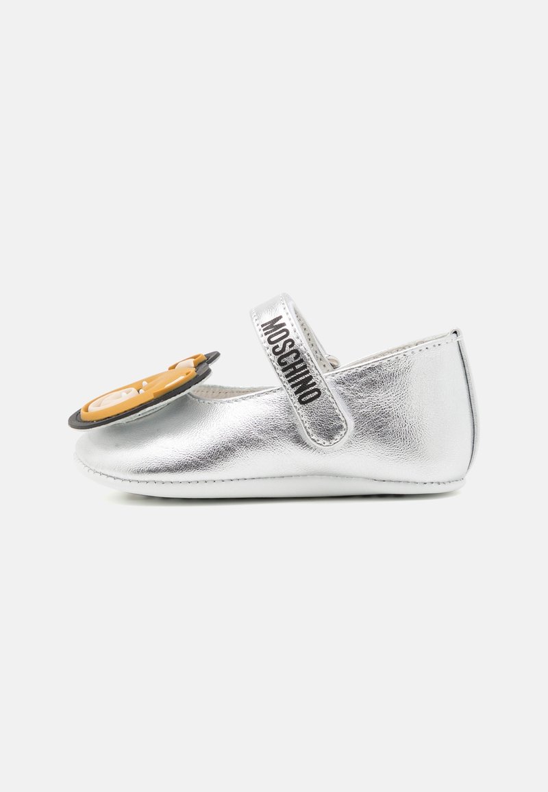 Chaussure bébé argentée avec bride Moschino et grand détail visage d'ours en peluche sur le devant, conçue pour les nourrissons.