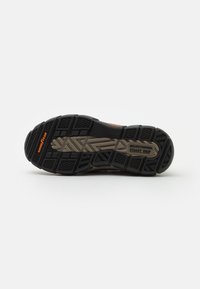 Talpa de pantof negru cu un model de profil dur, prezentând elemente de prindere texturate și o intermediară bej. Include branding-ul "GoodYear" și "Steady Grip".
