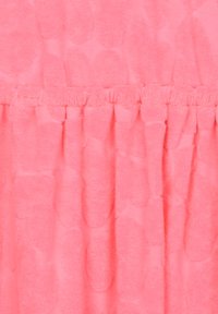 Tissu de corail rose texturé avec une surface douce et pelucheuse. Le design présente des motifs ovales, avec des sections froncées le long du haut.