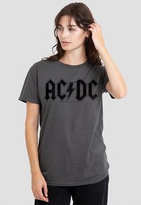 Graues Baumwoll-T-Shirt mit einem schwarzen AC/DC-Logografik und Blitz. Kurze Ärmel, runder Ausschnitt, lockere Passform.