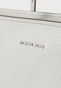 Γκρι τσάντα χειρός από δέρμα με υφή πετρωμάτων, με ασημένιο λογότυπο «Michael Kors», σχεδιασμό με δομή και διακριτική λεπτομέρεια υφής.