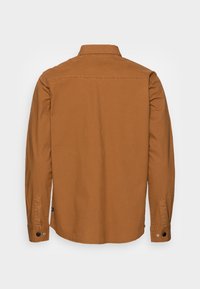 Brun långärmad skjorta i bomull med klassisk krage, knäppta ärmslut och en enkel, enfärgad design.