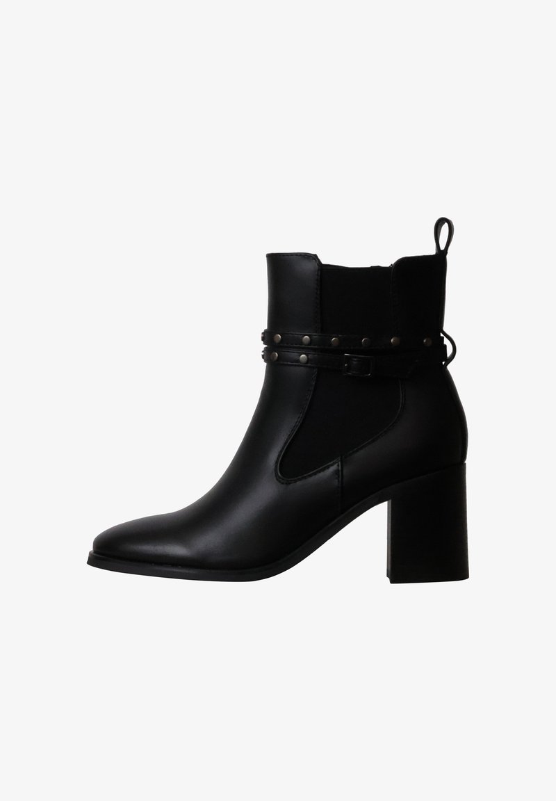 Bottine en cuir noir avec talon bloc, bride, détails en clous métalliques et languette à l’arrière.