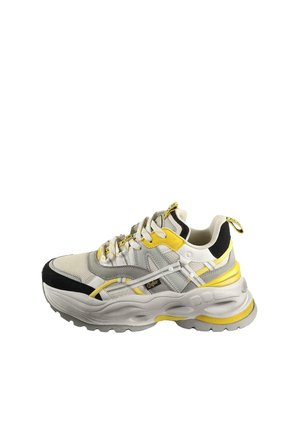 White and black chunky sneaker with yellow accents, textured fabric upper, thick sole, and logo detailing on the side and tongue.