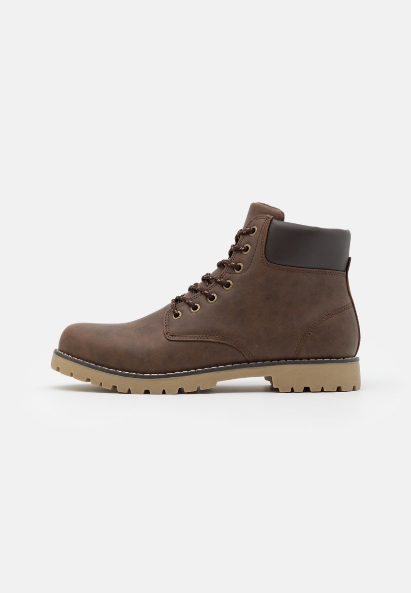 Bottine marron à lacets avec col noir rembourré et semelle beige robuste, vue de profil sur fond blanc uni.
