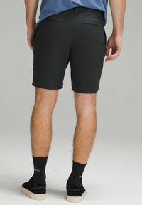 Czarne szorty wykonane z lekkiego materiału, o gładkiej strukturze i dwóch tylnych kieszeniach. Noszone z czarnymi skarpetkami i czarnymi butami.