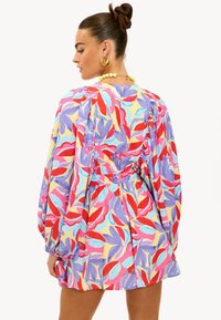 Robe multicolore avec motifs feuillus, manches bouffantes, taille froncée et coupe décontractée. Couleurs comprises : rouge, bleu, rose et jaune.