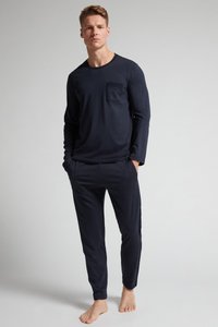 Marineblaues Langarmoberteil mit einer Brusttasche, kombiniert mit passenden Hosen mit elastischem Bund, beide aus weichem Stoff für Komfort. Barfußmodell.