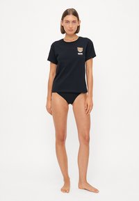 Black cotton t-shirt featuring a bear graphic on the chest, round neckline, and short sleeves, paired with black bikini bottoms.
