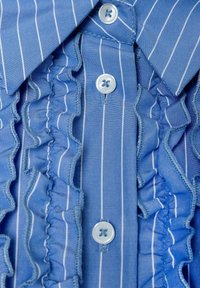 Blauwe gestreepte shirt met gerimpelde versieringen, voorzien van zes ronde lichtblauwe knopen en een puntige kraag. Gevoelige stofdetails zichtbaar.