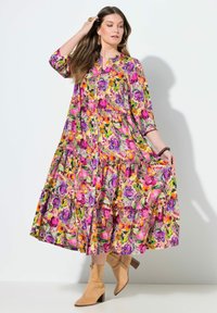 Květinové maxi šaty s živými růžovými, fialovými a žlutými vzory, vrstveným designem, zapínáním na knoflíky vpředu a tříčtvrtečními rukávy.