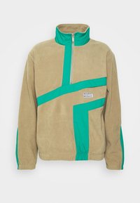 Fleece-pullover i tan med grønne accenter, med halvlynlås, ståkrave og geometrisk mønster over forsiden.