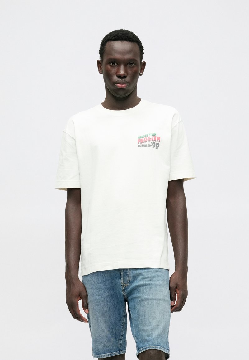 Λευκό βαμβακερό T-shirt με κοντά μανίκια που διαθέτει πολύχρωμο κείμενο "FOREST HILLS FROGJAM QUEENS NY 99" στην αριστερή περιοχή του στήθους.