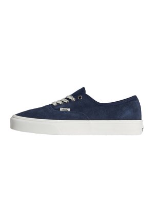 Mørkeblå ruskind Vans lav-top sneaker med hvid gummisål og hvide snørebånd, vist i profil på hvid baggrund.