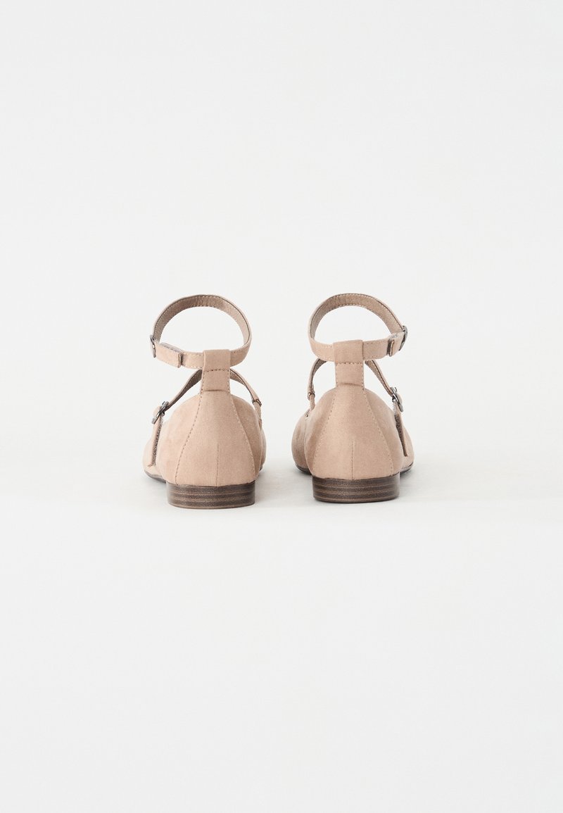 Beige Wildleder-Ballerinas mit runder Zehenpartie, Knöchelriemen und kleinem Absatz. Die Rückansicht zeigt eine glatte Oberfläche und ein minimalistische Design.