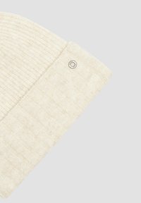 Cream knit beanie with a textured pattern and a folded cuff, featuring a small silver logo accent on the side.