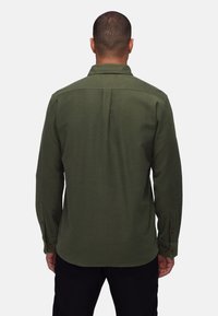 Groene blouse met lange mouwen, een kraag, knoopmanchetten en een gestructureerde afwerking. Heeft een centrale naad op de rug voor extra ontwerpfactor.