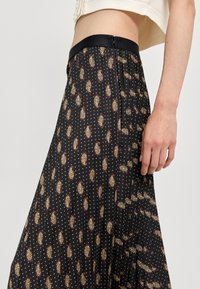 Zwarte rok met paisley- en stippenpatroon. Geplooid ontwerp, met een soepele tailleband en een zijrits. Lichtgewicht materiaal.