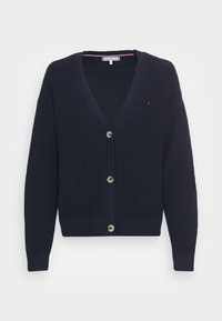 Mörkblå stickad cardigan med V-ringning, fem stora knappar, ribbade ärmslut och nederkant. Har en subtil strukturerad mönster och varumärkesdetalj.