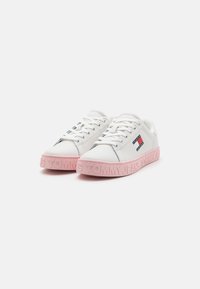 Weiße Sneakers mit einem glatten Lederoberteil, ausgestattet mit einer pinkfarbenen Gummisohle, die mit "TOMMY JEANS" geprägt ist. Enthält subtile Farbakzente an den Seiten.