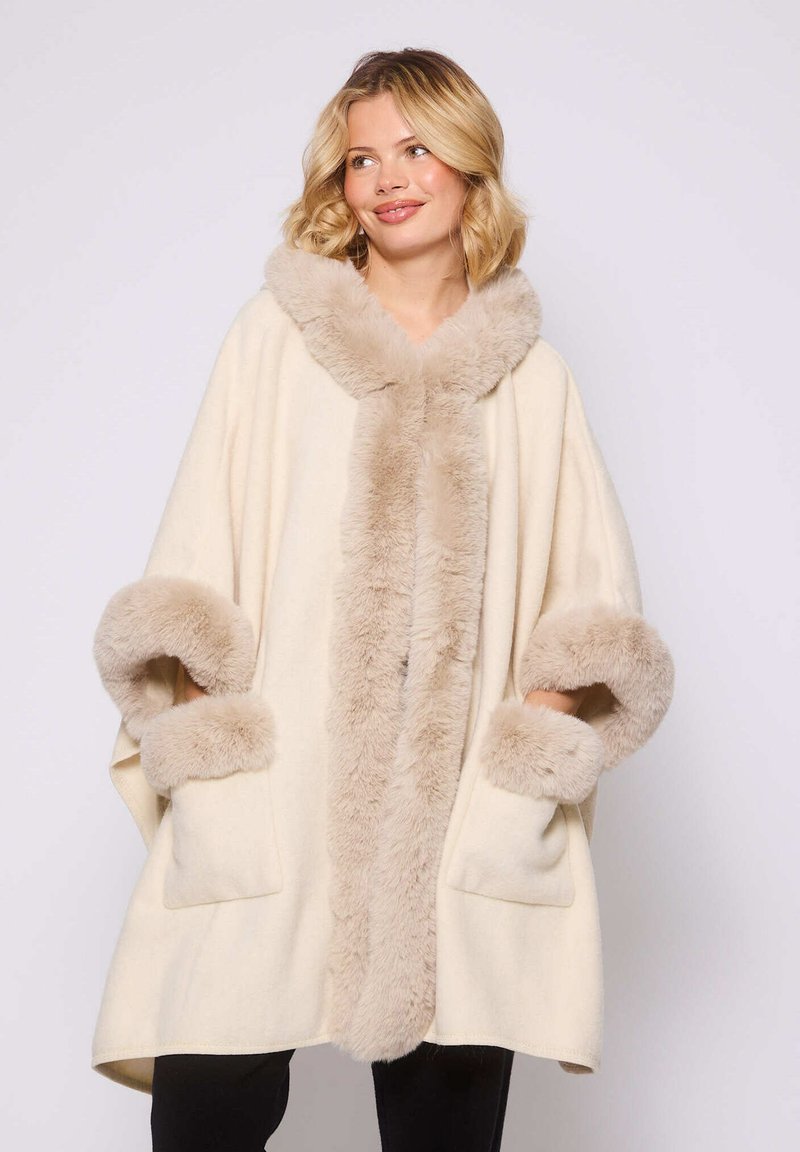 Poncho de color crema de gran tamaño con un suave borde de piel sintética beige en la capucha y las mangas. Cuenta con bolsillos y una silueta relajada.