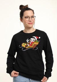 Felpa nera con una grafica colorata di un personaggio dei cartoni animati in una slitta con un cane, circondato da regali e un albero di Natale.