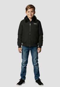 Sort bomberjakke med en imiteret pelskrave, der har en lynlåslukning foran, ribkanter ved ærmerne og en logopatch. Kombineret med lyseblå jeans og sneakers.