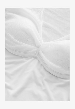 Bijeli grudnjak s čipkastim premazom i glatkim košaricama. Tkanina je mekana s nježnom teksturom, s naboranim šavom u sredini.