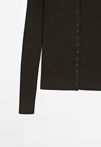 Donker geribde cardigan van zacht materiaal, met een knoopsluiting aan de voorkant, lange mouwen en een aansluitende zoom. De knopen zijn in een bijpassende donkere kleur.