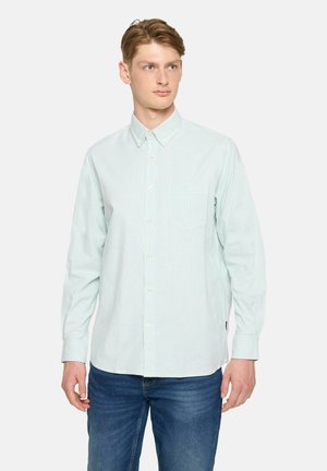 Lys grøn stribede skjorte med knapåbning, krave, enkelt brystlomme og lange ærmer, parret med blå jeans. Materiale af bomuldsblanding.