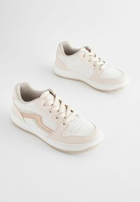Jasnobeżowe sneakersy wykonane z skóry i siateczki, z wiązanym zapięciem, perforowanym noskiem i teksturowaną gumową podeszwą. Akcentowane kremowym paskiem po boku.