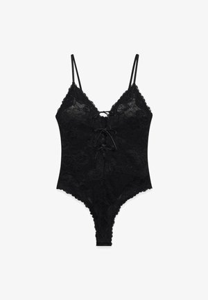 Bodysuit en dentelle noire avec bretelles spaghetti réglables, motif floral, décolleté en V profond et détail lacé à l'avant. Dos plus échancré.
