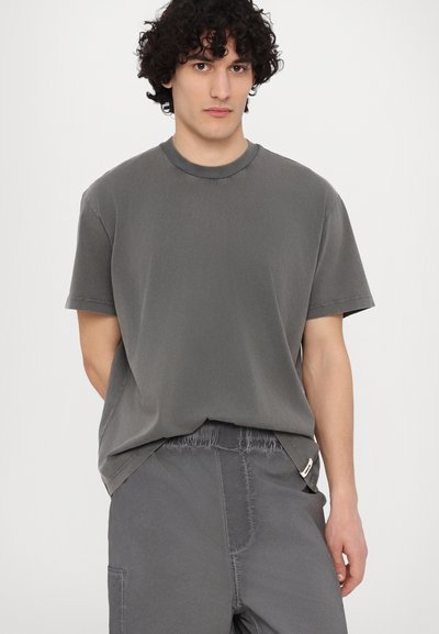 Grå t-skjorte med kort erm og ribbestrikket rund hals med løs passform, sammen med matchende grå shorts med elastisk liv.