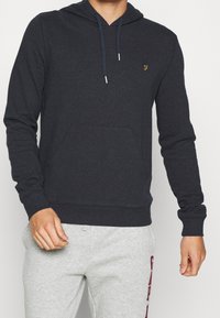Sweat-shirt à capuche bleu marine en mélange de coton, avec une poche avant, des cordons de serrage et un petit logo doré sur la poitrine.