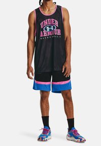 Muž v černém bezrukávovém síťovém basketbalovém dresu s růžovým lemem a nápisy, černých a modrých šortkách, černých ponožkách a vícebarevných teniskách.