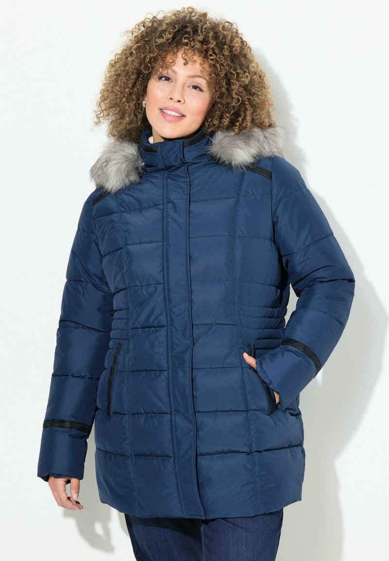 Mörkblå puffjacka med grå fuskpäls på huvan, fickor med dragkedja och ribbstickad detalj vid ärmsluten. Quillterat mönster genom hela jackan.