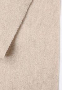 Tessuto in feltro beige con una texture morbida, che mostra una piega stratificata. La superficie è liscia, con un aspetto leggermente peloso lungo i bordi.