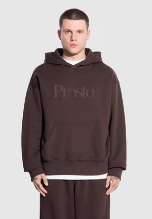 Brązowa hoodie wykonana z miękkiego materiału, z kieszenią z przodu i logo marki "Prosto". Nadrukowane akcenty nad kieszenią. Prosty design.