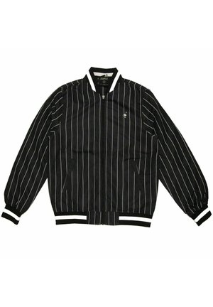 Mustassa bomber-takissa on valkoiset pystysuorat raidat, ribbaat hihansuut ja vyötärö, vetoketjukuitti edessä sekä pieni logoyksityiskohta vasemmassa rinnassa.