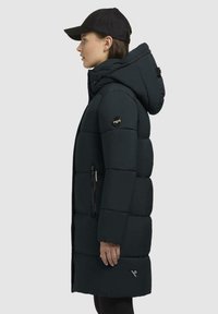 Palton negru tip puffer cu glugă, cu secțiuni matlasate, buzunare cu fermoar, patch cu logo pe mânecă și o siluetă dreaptă.