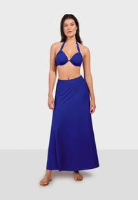 Modrý bikiny top s viazaním za krk v kombinácii s dlhou modrou sukňou, obidve z hladkého a pružného materiálu, pričom sukňa má bočný rozparok pre pohodlný pohyb.
