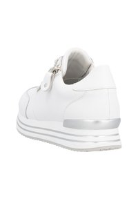 Sneaker blanche avec un dessus synthétique lisse, fermeture éclair, accents argentés et un design de semelle superposée avec une texture épaisse.