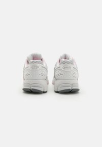 Białe i szare buty sportowe z różowymi akcentami, posiadające teksturowaną siateczkową cholewkę oraz amortyzowaną podeszwę z wyraźnym wzorem bieżnika.