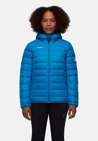 Veste rembourrée bleue avec capuche, design matelassé, fermeture éclair avant et logo sur la poitrine gauche. Présente des poignets élastiques et une coupe ajustée.