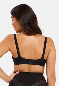 Soutien-gorge noir en tissu lisse avec bretelles ajustables. Dispose d'une fermeture à crochets à l'arrière et d'un design simple sans embellissements.