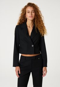 Zwart cropped blazer met één knoop, gesneden revers en lange mouwen; gecombineerd met bijpassende à la carte broek. Soepele stof textuur.