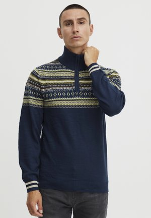 Mornarica zip-vest sa uzorkom boja na prsima, s geometrijskim dizajnom u zelenoj, žutoj i bijeloj boji. Rebrasti manžeti i donji rub.