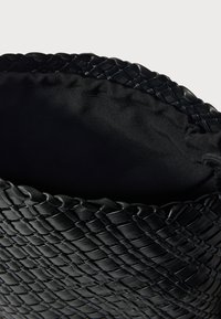 Πλεκτή μαύρη δερμάτινη τσάντα με στρογγυλεμένη κορυφή και απαλό εσωτερικό επένδυση. Διαθέτει υφή που μοιάζει με καλάθι και δεν έχει ορατά μεταλλικά στοιχεία.