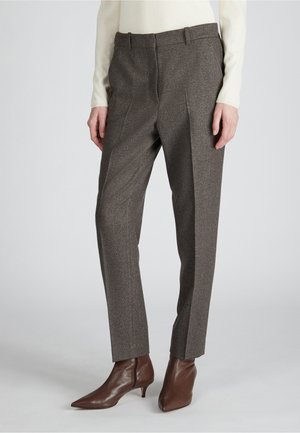 Braune, strukturierte Hose mit taillierter Passform, die Falten und einen Bund aufweist. Kombiniert mit braunen, spitz zulaufenden Ankle-Boots.
